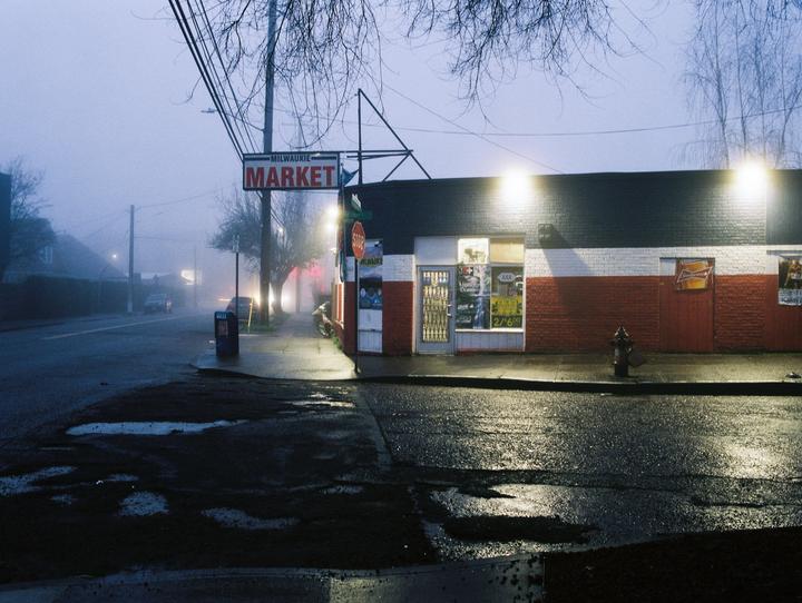 A foggy street scene shows a market with a red and white facade and a street sign that reads "Milwaukie Market."