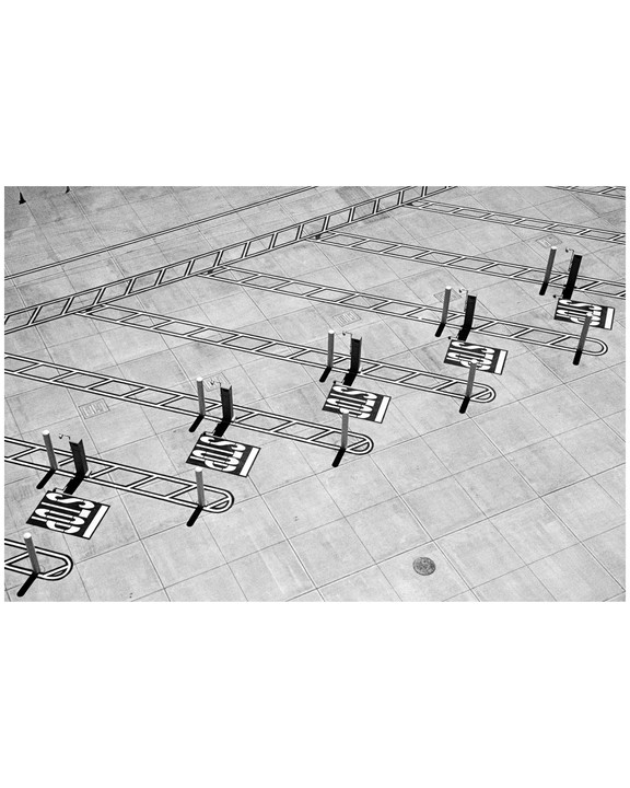 A high-angle view shows a tiled ground with a pattern of lines and several posts casting long shadows.