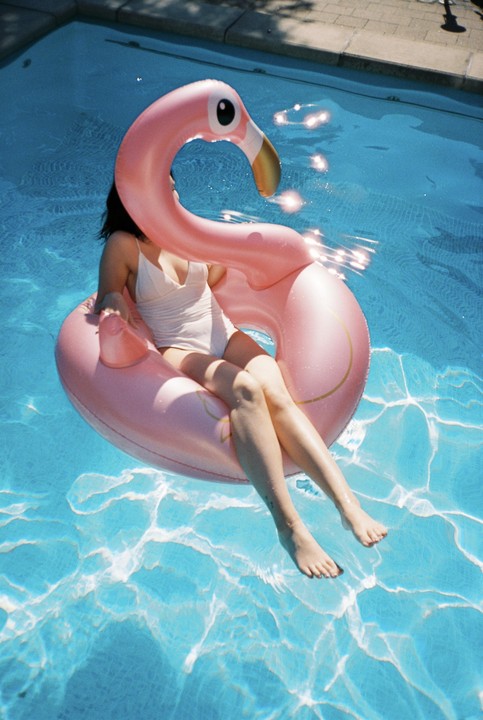 A woman floats in a swimming pool on a pink flamingo inflatable.