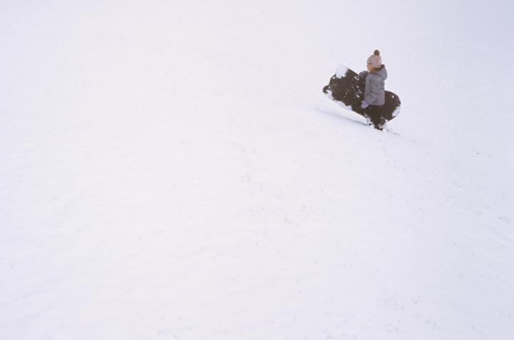 A child sits on a sled shaped like an animal in a snow-covered field.