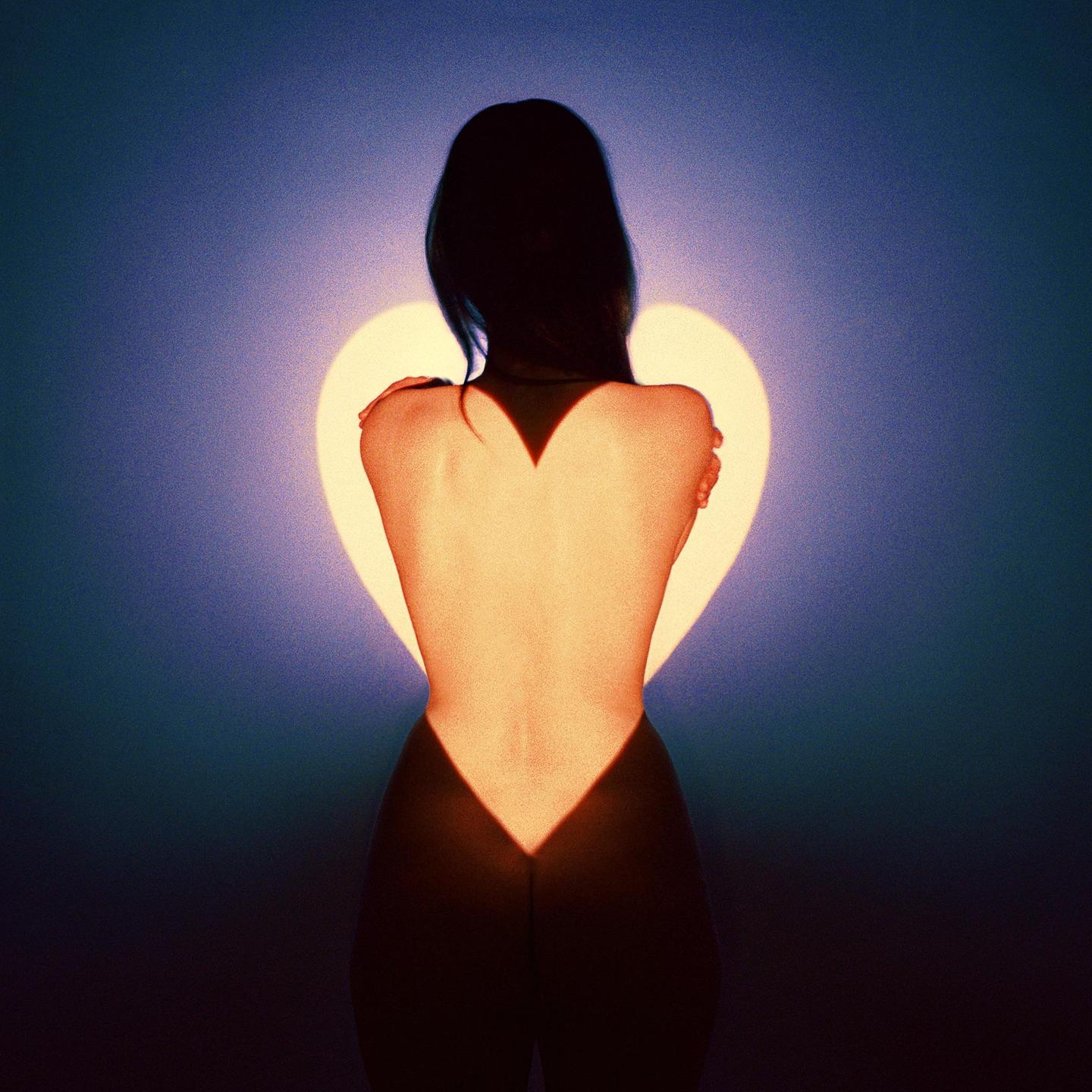 A woman stands with her back to the viewer, illuminated by a heart-shaped light.