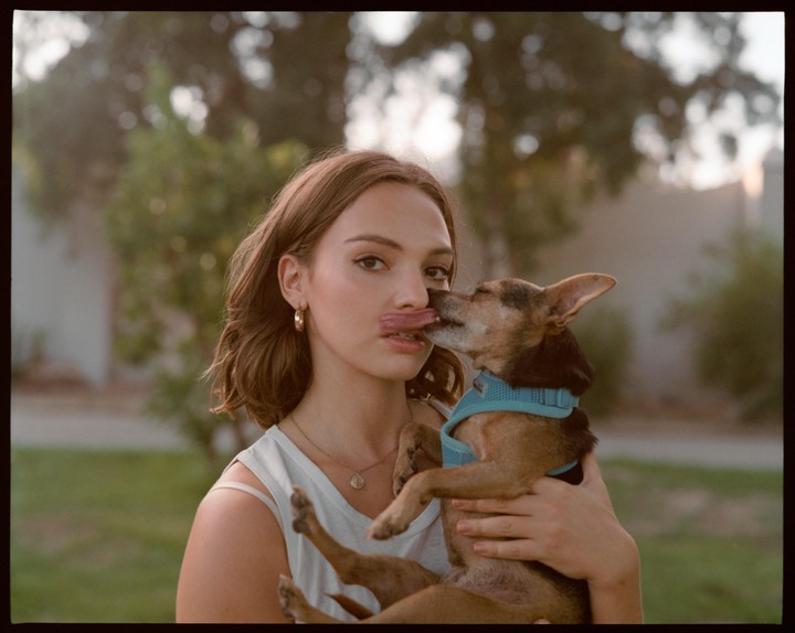 A small dog licks a woman's face as she holds it in her arms.