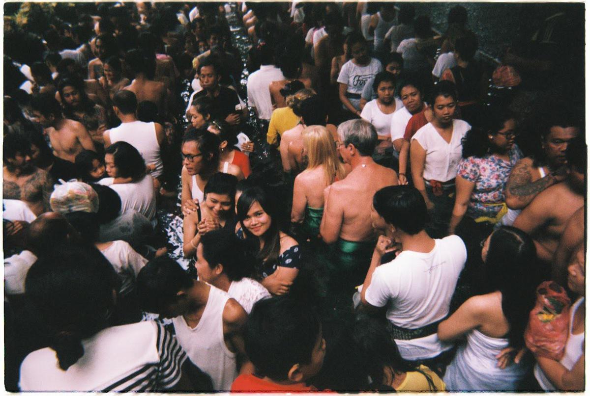 A large crowd of people are standing in water, with some looking towards the camera.