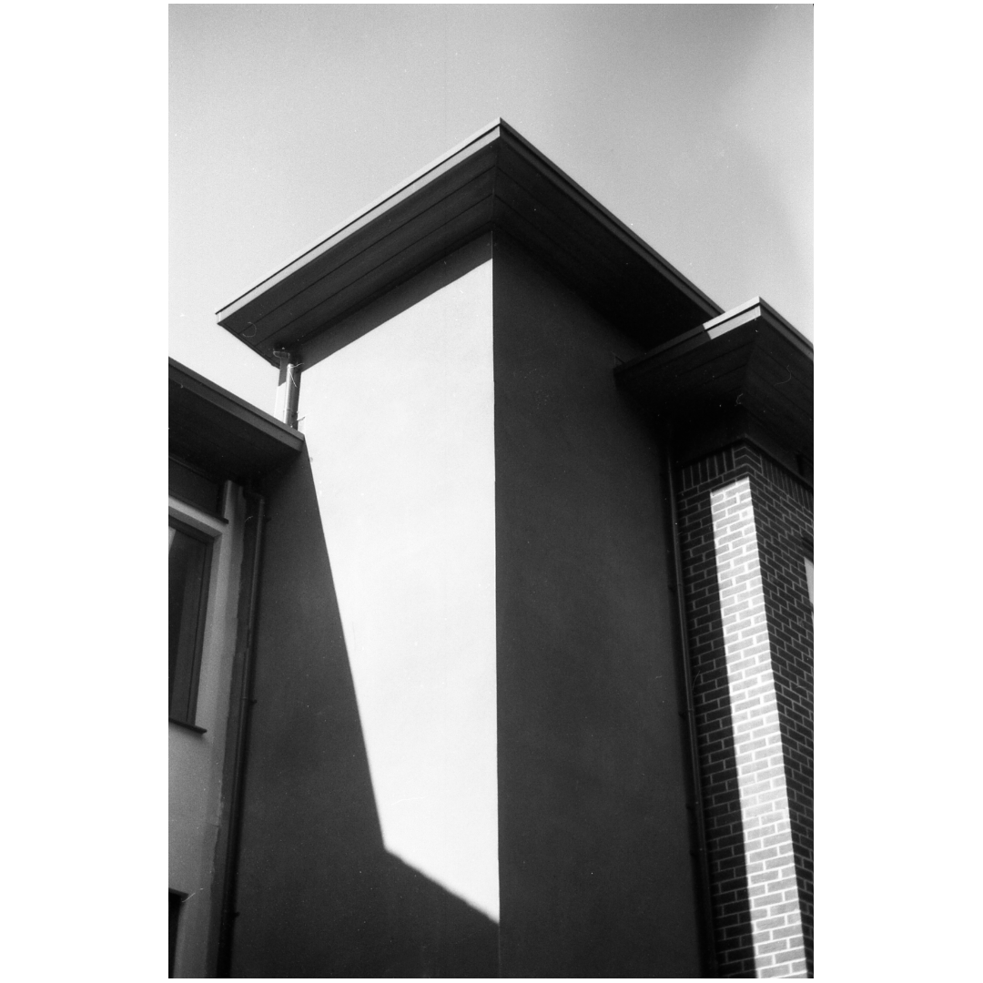A low-angle view of a building facade shows strong shadows and architectural details.