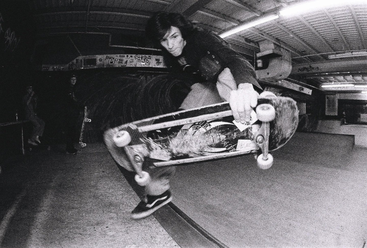 A skateboarder performs a footplant trick in a skatepark.