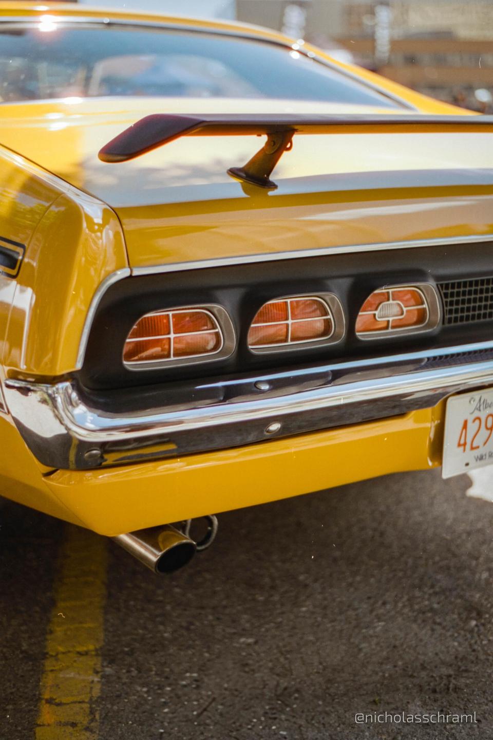 The rear of a yellow Mercury Cyclone is parked on asphalt with a license plate visible.