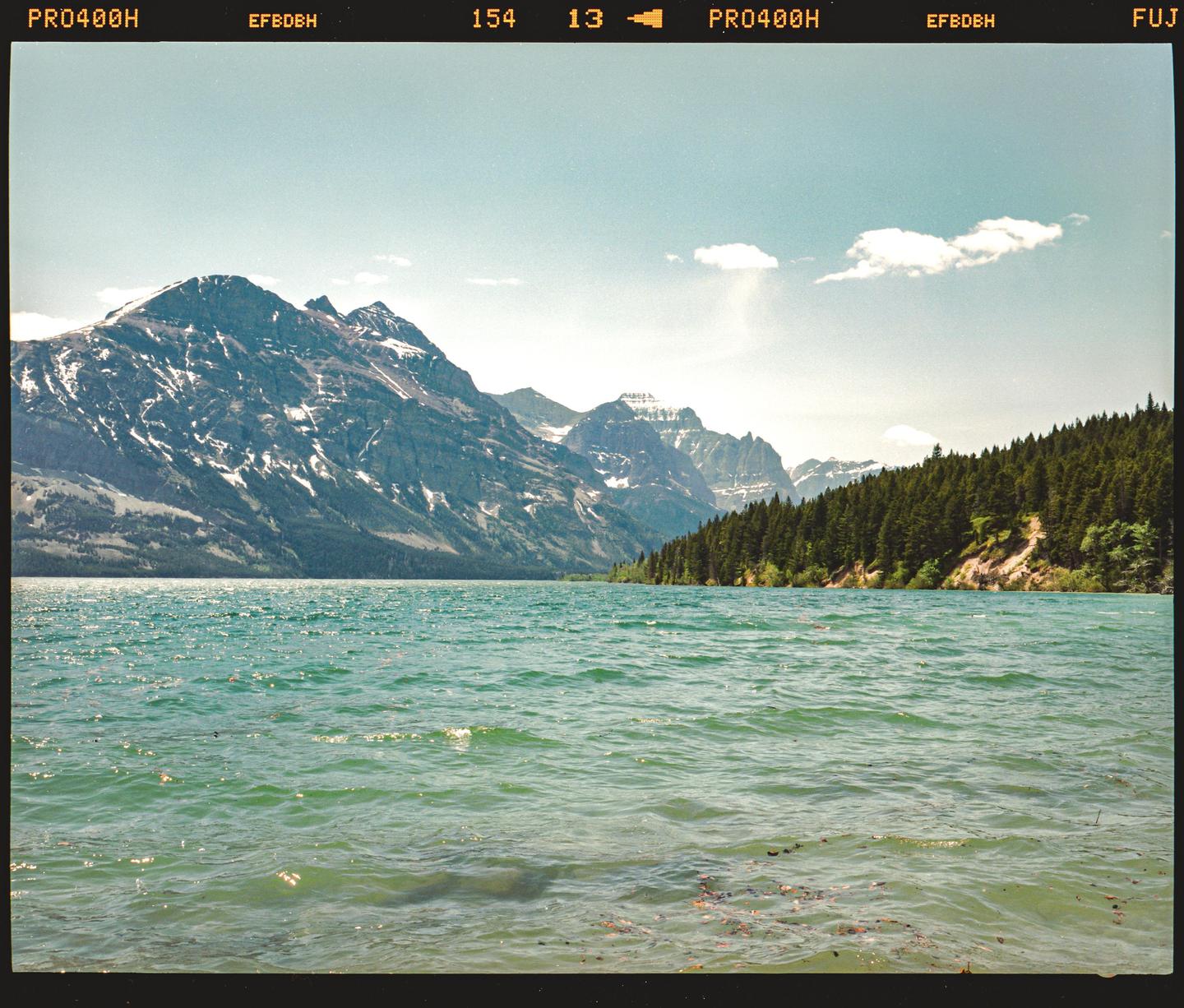 A large body of water with mountains and a forest in the background.