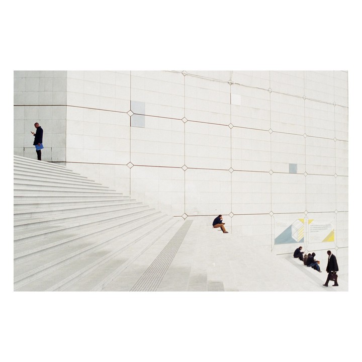 Several men are on a large white staircase and wall with geometric patterns.