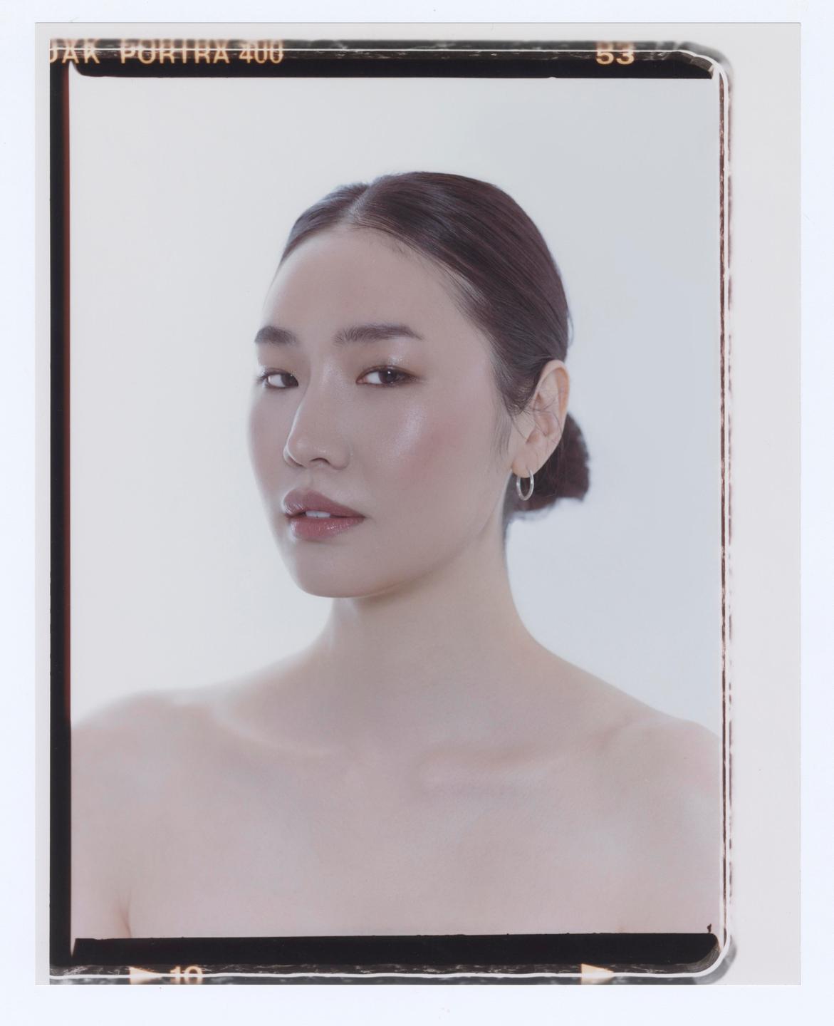 A woman with her hair pulled back looks directly at the viewer.
