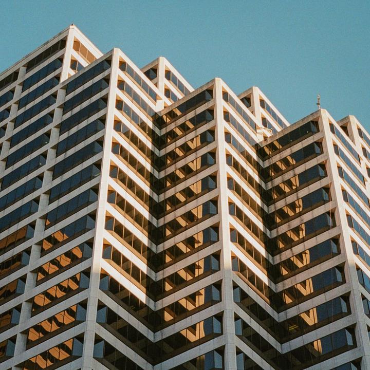 A tall building with many windows reflects the sunlight.