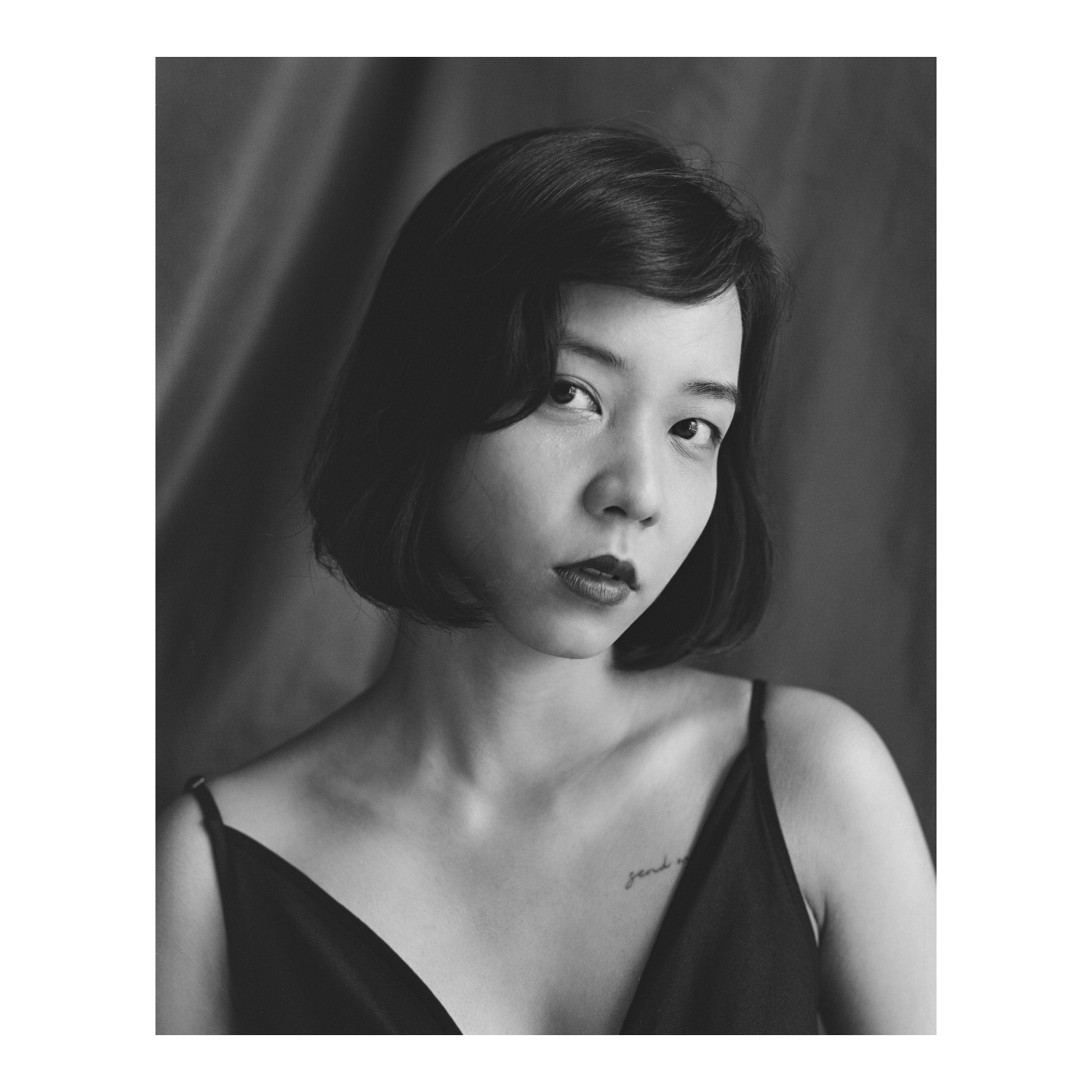A woman with short hair and dark lipstick looks directly at the viewer.
