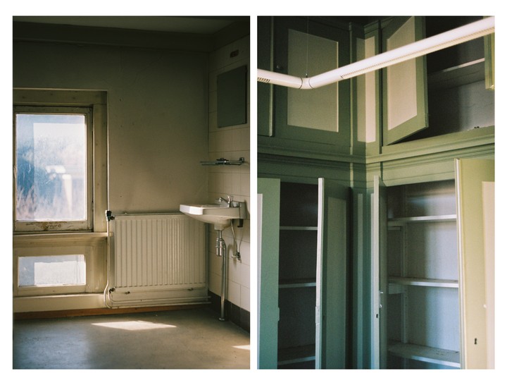 Sunlight streams through a dirty window into an empty room with a sink and radiator, next to a corner with open cabinets.