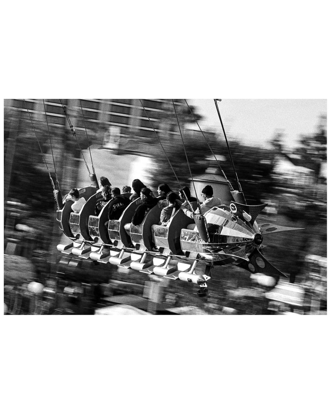 A group of people ride a rocket-shaped amusement park ride that is in motion.