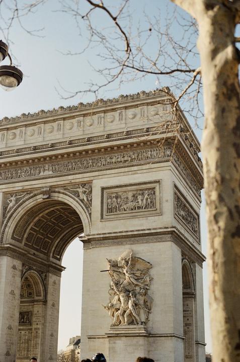 The Arc de Triomphe is partially visible behind a tree and a street lamp.