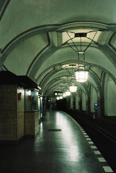 A subway platform with arched ceilings and hanging lamps extends into the distance.