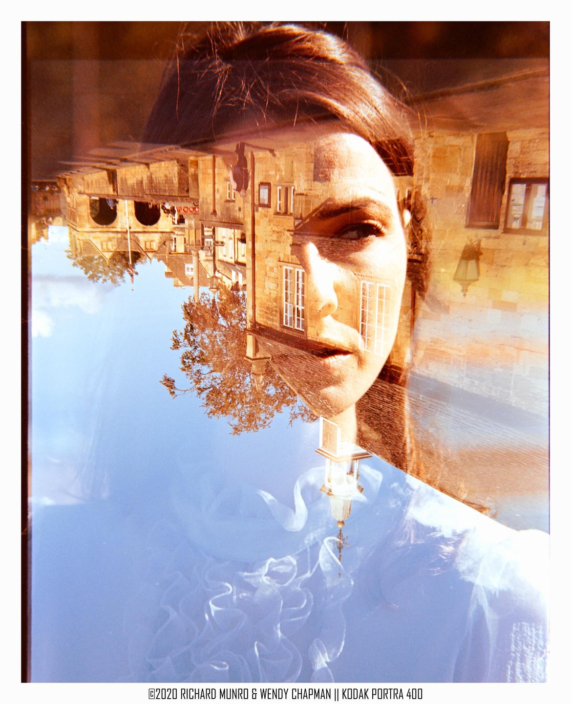 A woman's face is double-exposed with an upside-down image of a stone building and a tree against a blue sky.