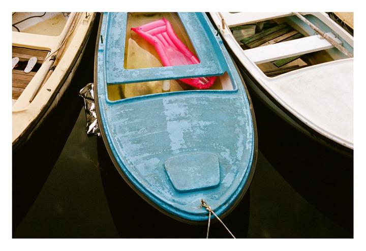 Three boats are tied together, with a pink inflatable raft visible in the middle boat.