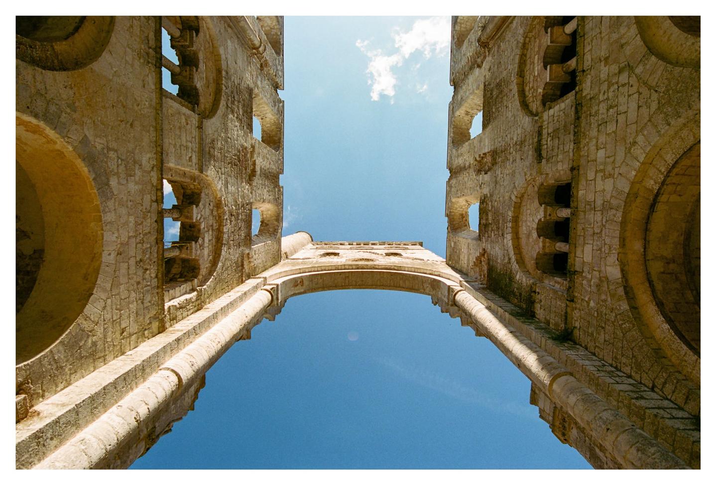 A low-angle view shows the ruins of an abbey against a bright blue sky.