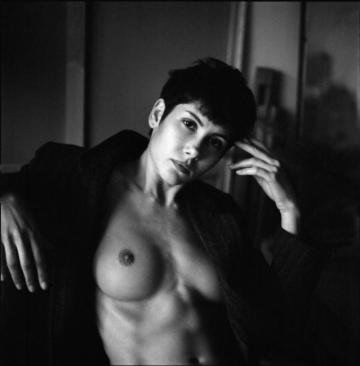 A woman with short hair and an open jacket poses for a portrait.