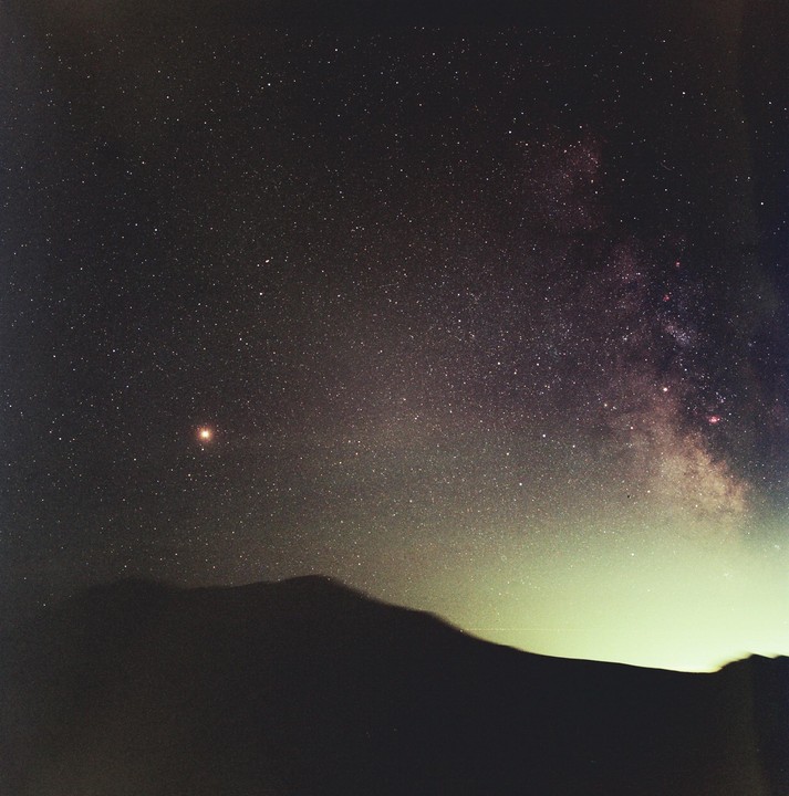 A mountain range is silhouetted against a night sky filled with stars and the Milky Way.
