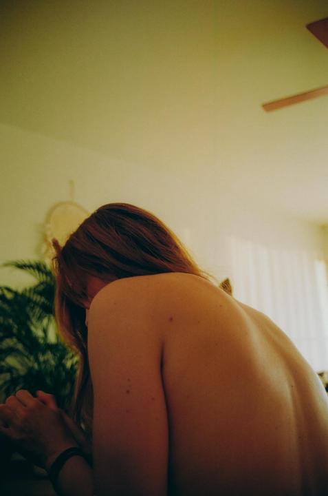 A woman with long hair is seen from behind, with her bare back visible.