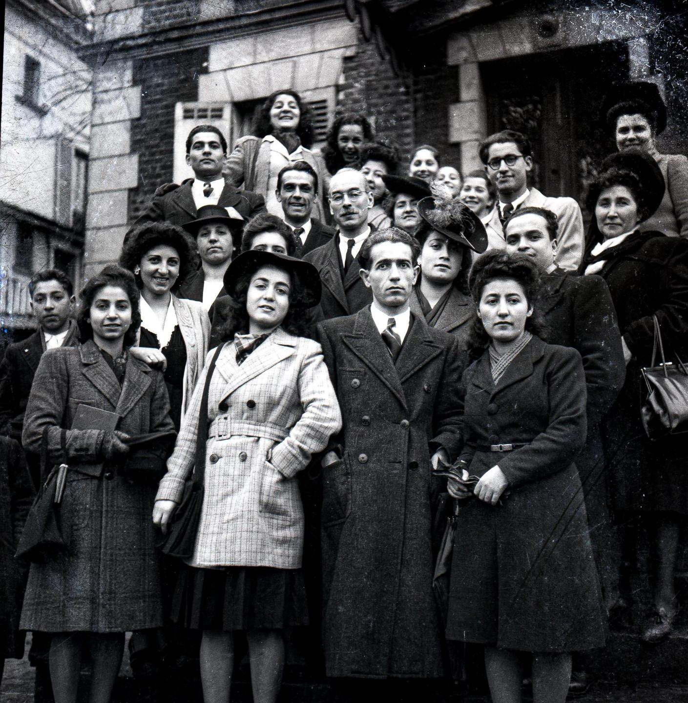 A large group of men and women pose for a group portrait on the steps of a building.