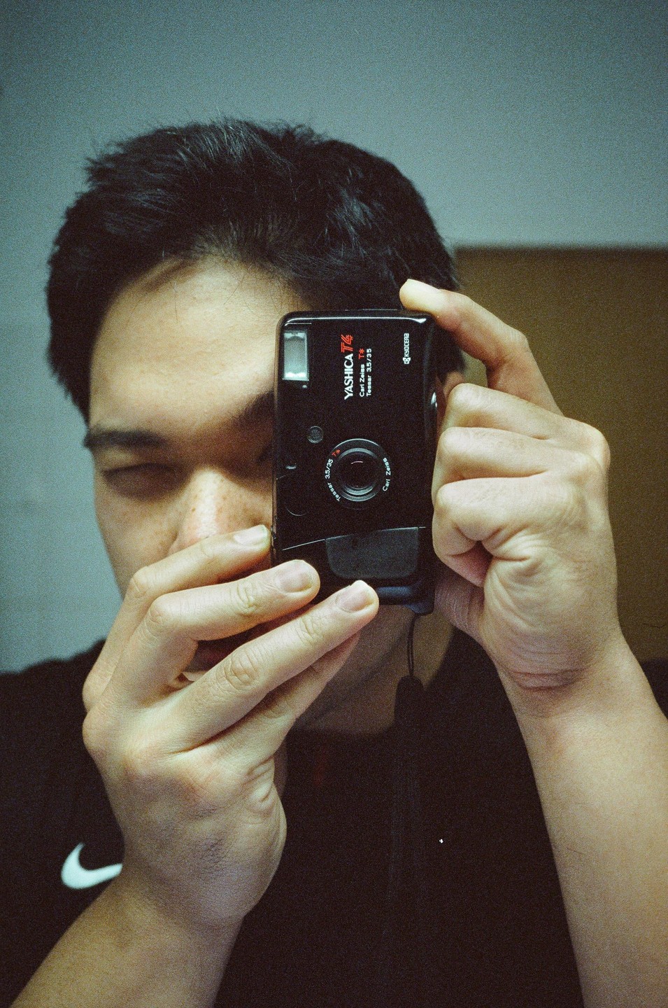 A man holds a black camera up to his face, obscuring one eye.