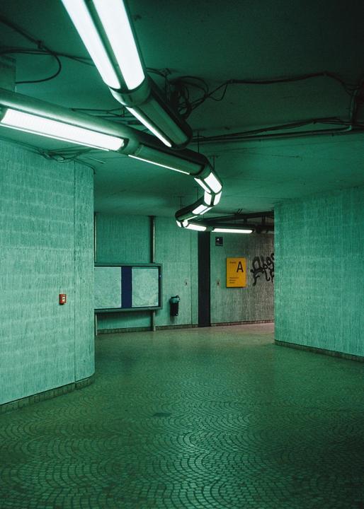 A curved hallway with fluorescent lights on the ceiling and a patterned floor is visible.