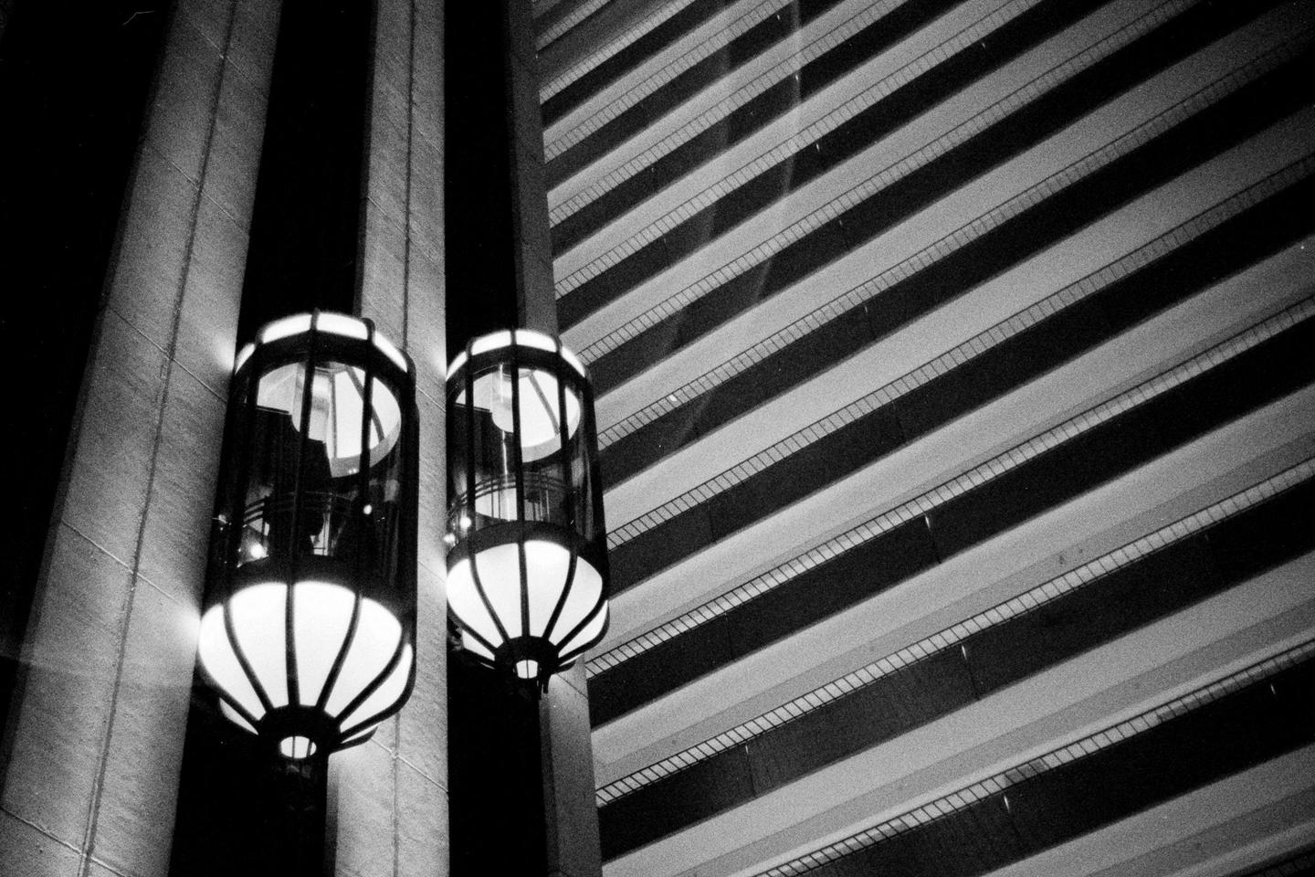 Two glowing elevators are visible next to a building with many floors.