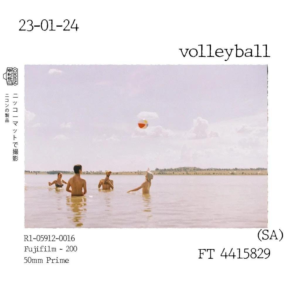 Four people are playing volleyball in a body of water under a cloudy sky.