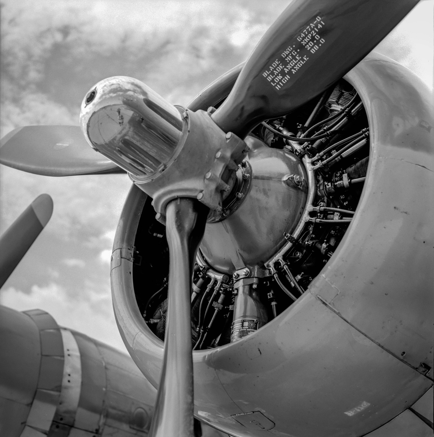 A close-up view of an airplane engine and propeller is shown against a cloudy sky.