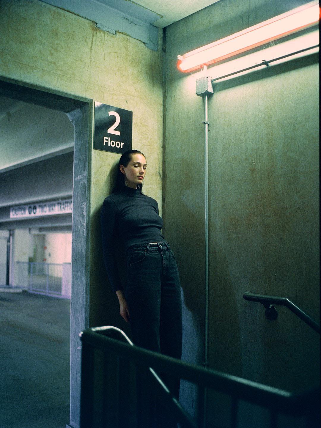 A woman stands in a stairwell next to a sign for the second floor.