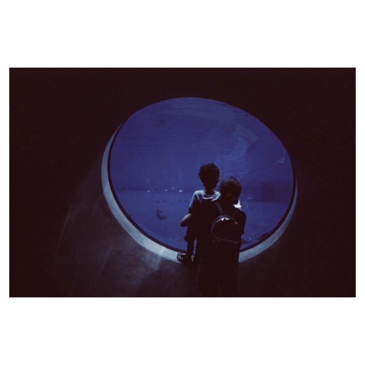 A woman and a boy look into a large circular aquarium.