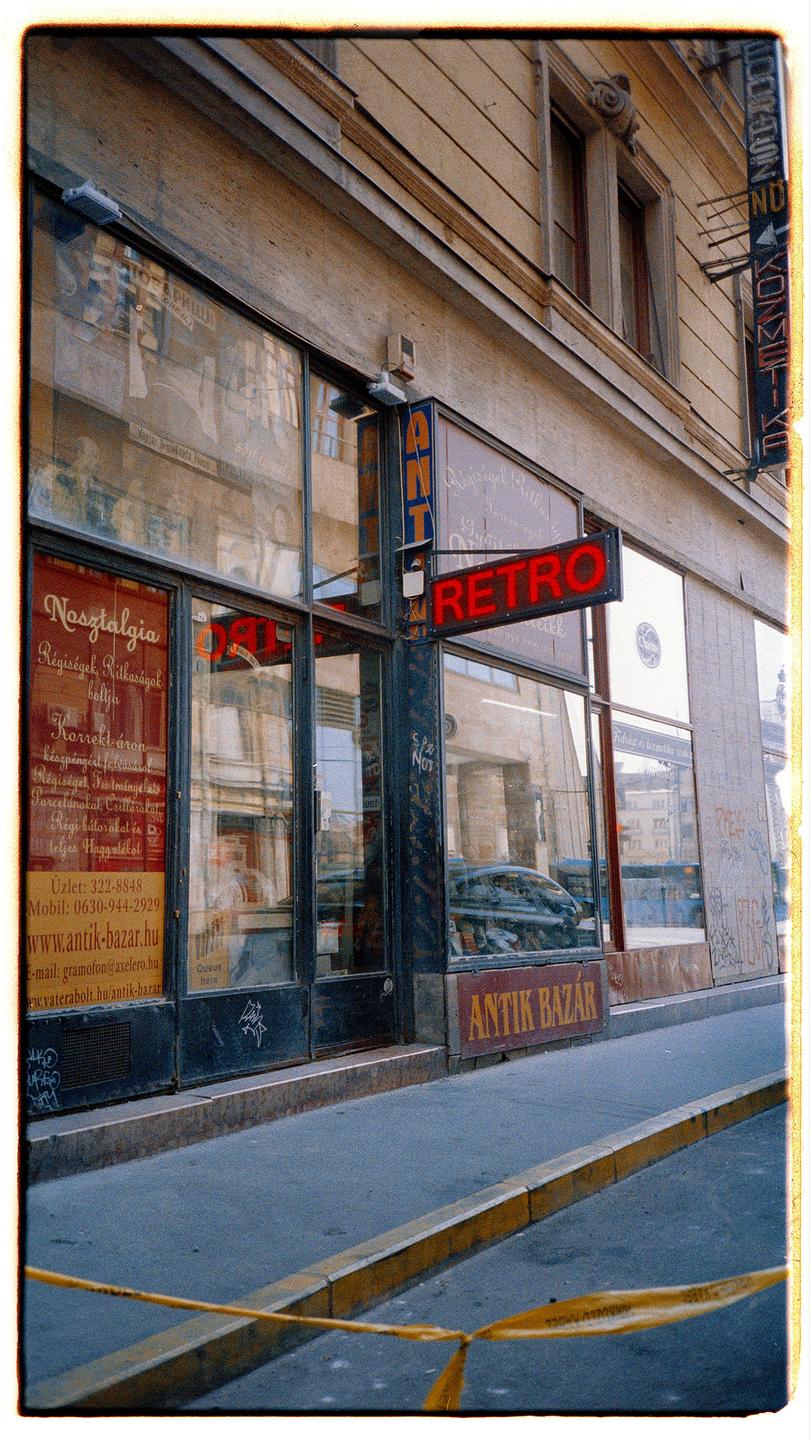 A storefront with a "RETRO" sign and reflections of buildings is visible from a street with a yellow curb.