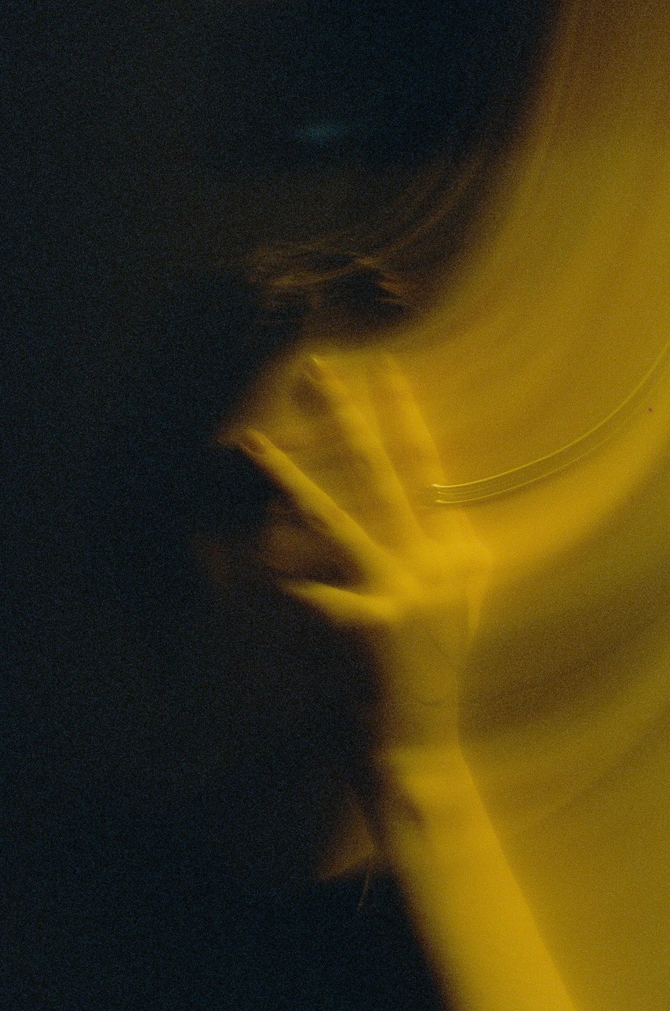 A hand with a ring is visible in a dark, blurry image with a yellow light source.