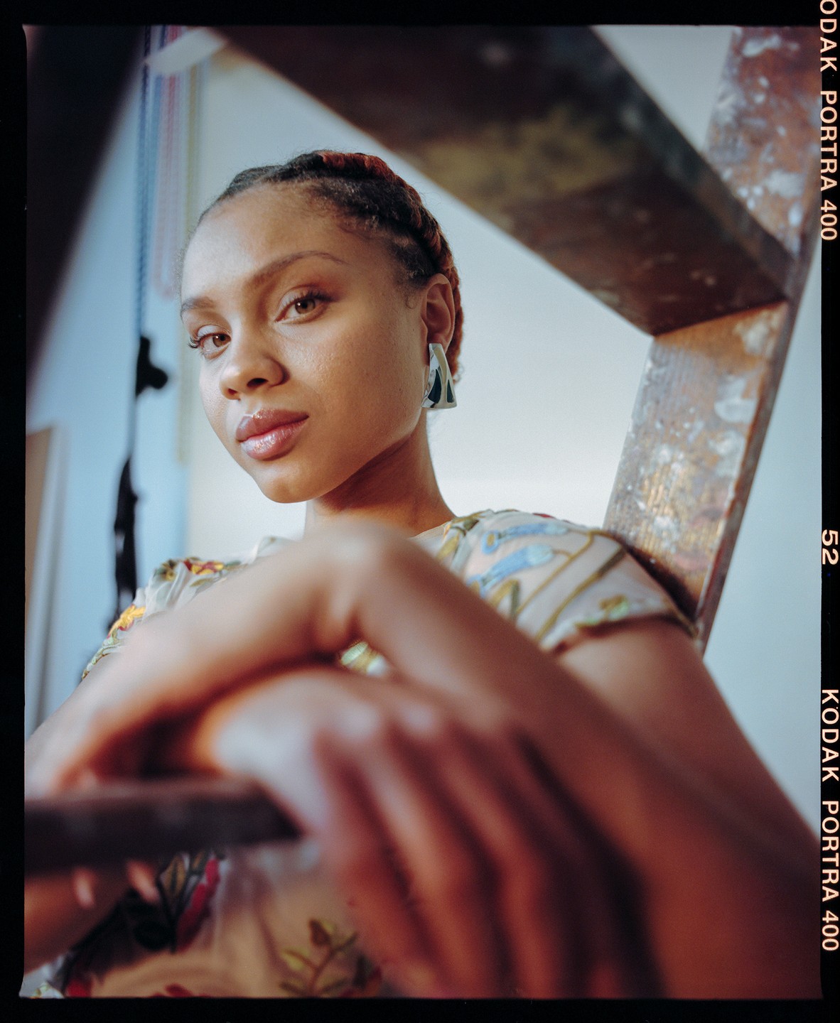 A woman with braided hair and a patterned shirt is looking at the viewer.