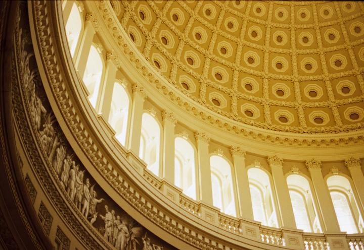 The ornate interior of a large dome features a coffered ceiling and a frieze with sculpted figures.