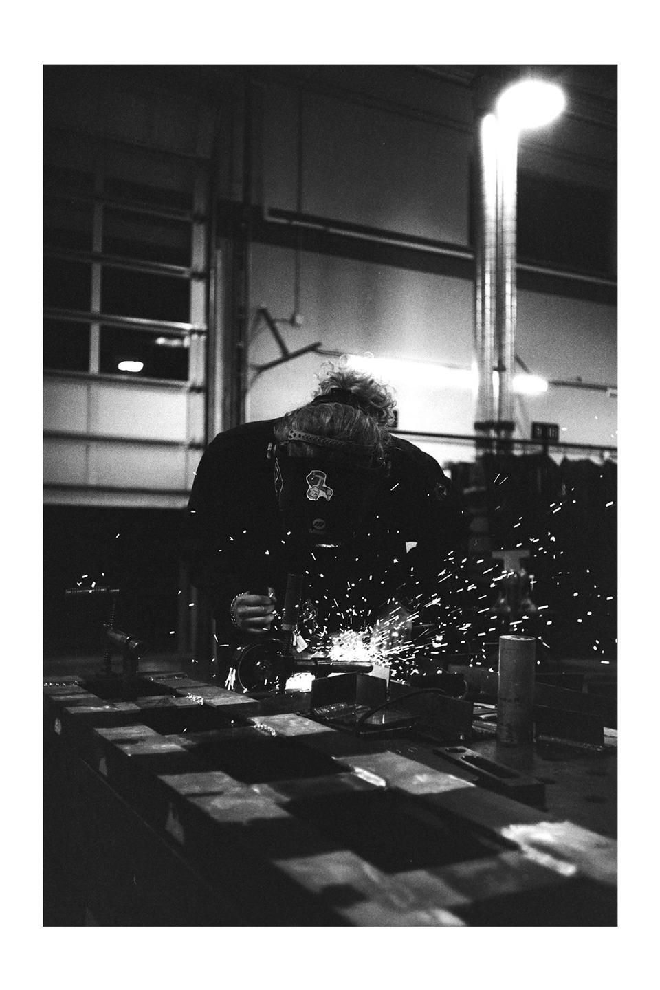 A person is welding metal in a workshop, creating bright sparks.