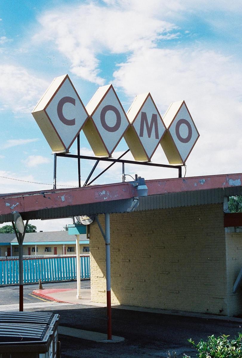 A sign with the word "COMO" in diamond shapes is visible above a building with a red awning.