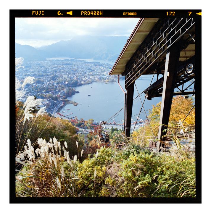 A scenic overview of a town and lake from a high vantage point, with a cable car station in the foreground.