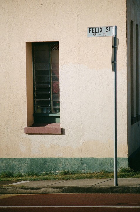 A street sign for Felix Street is next to a building with a window and a green base.