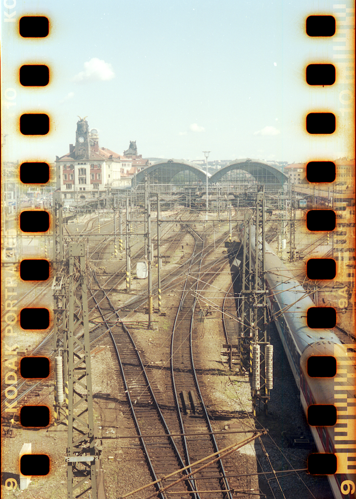 A train station with multiple tracks and a train is visible under a clear sky.