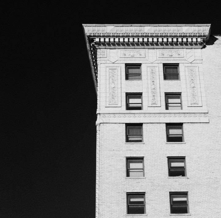 A tall building with many windows is shown against a dark sky.