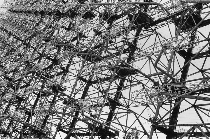 A large, complex metal structure with many interconnected beams and platforms is shown against a bright sky.