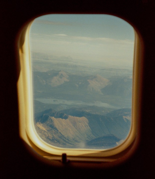A view of mountains and a lake from an airplane window is visible.