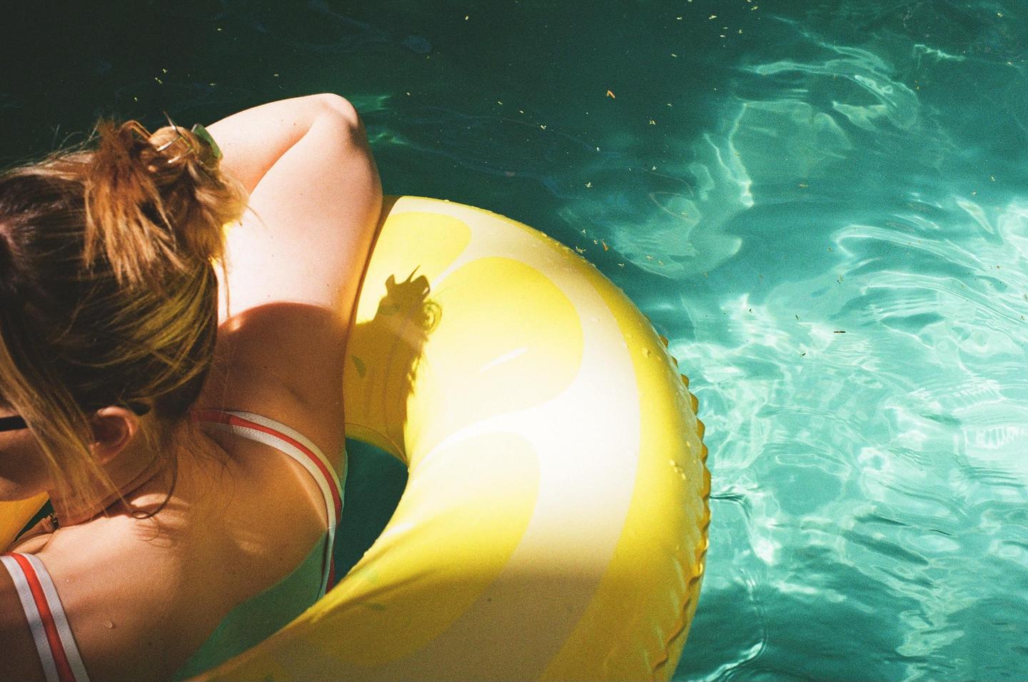 A woman floats on a lemon-shaped inflatable in a swimming pool.
