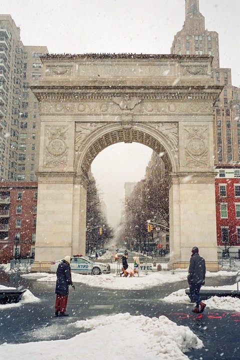 Snow falls on the Washington Square Arch and surrounding streets in New York City.