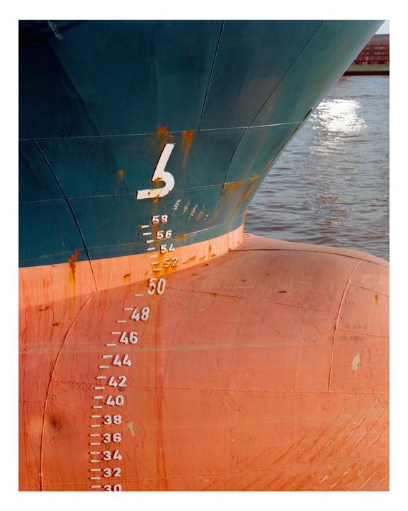 The bow of a large ship with draft markings is visible above the water.
