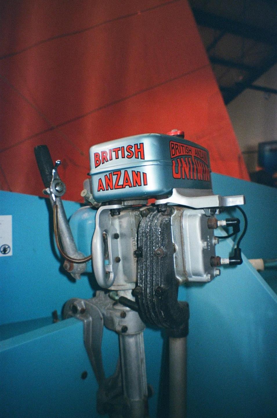 A close-up shot shows a British Anzani outboard motor with a red background.