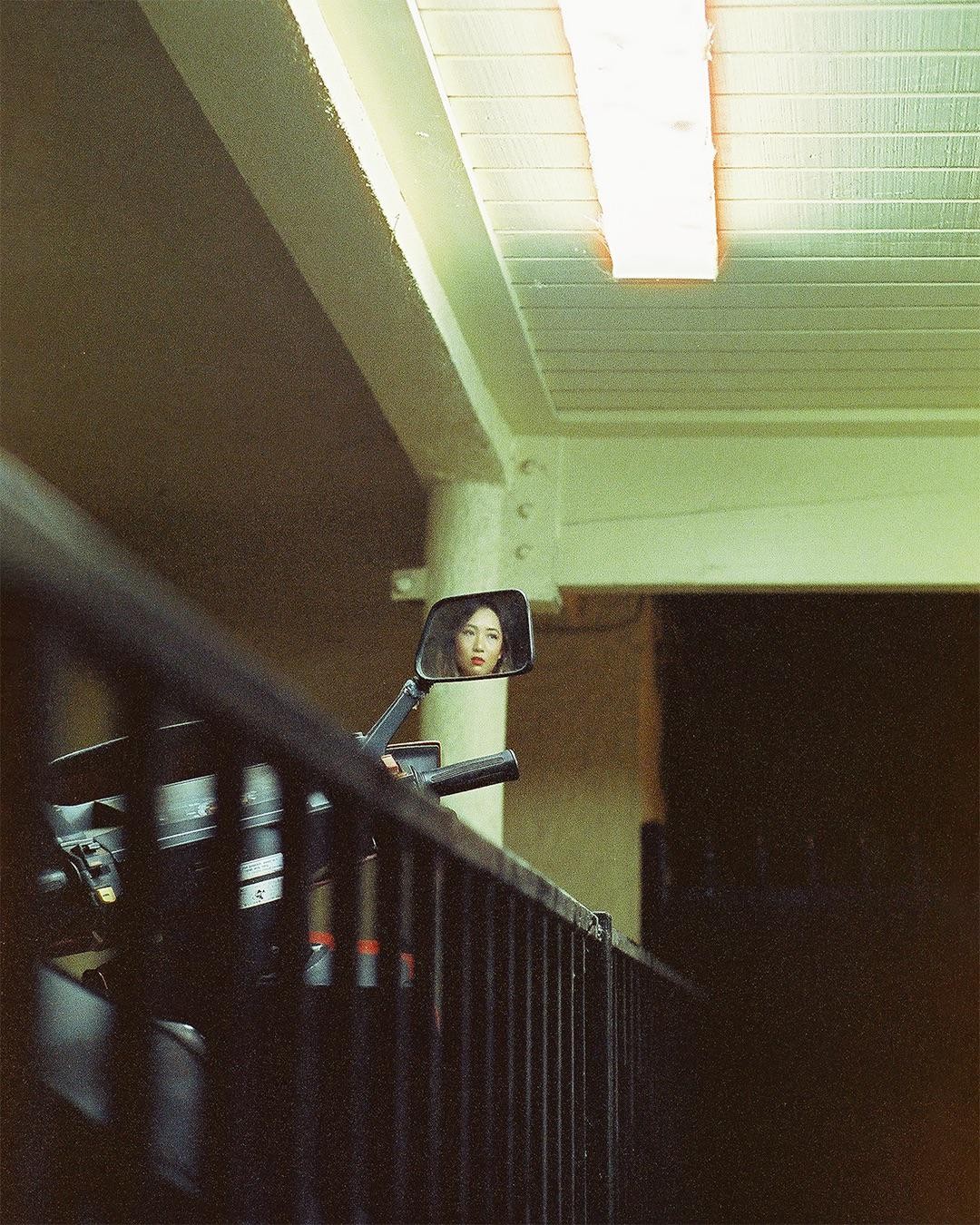 A woman's face is reflected in a motorcycle mirror.